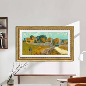 K&ouml;nnte beinhalten: Ein gerahmter Druck eines Landschaftsgem&auml;ldes mit einem gelben Haus, einer Steinmauer und einer Figur auf einem Feld. Das Kunstwerk hat einen goldenen, verzierten Rahmen und wird an einer wei&szlig;en Wand ausgestellt. Das Gem&auml;lde hat eine helle, sonnige Farbpalette.