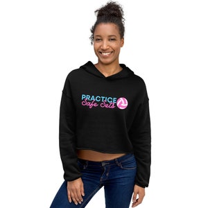 Könnte beinhalten: Schwarzer, kurzer Hoodie mit einem weißen Volleyball-Motiv und dem Text "PRACTICE Safe Sets" in rosa und blauen Buchstaben.