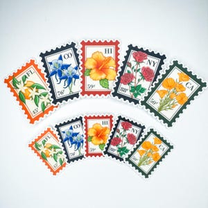May include: A collection of floral-themed stickers resembling postage stamps. Each sticker features a different state flower, including orange blossoms, columbines, hibiscus, roses, and California poppies. The stickers have a white background and are outlined in various colors.