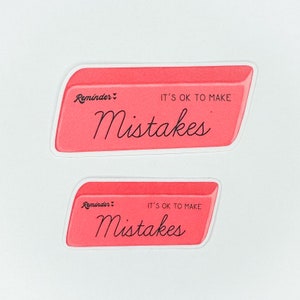 May include: Two pink eraser stickers with white borders. The top sticker says "Reminder: It's ok to make mistakes". The bottom sticker says "Reminder: It's ok to make mistakes".