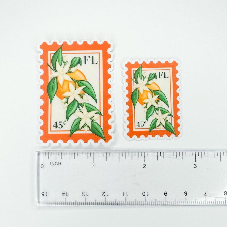Op de afbeelding: Twee postzegels met sinaasappelbloesem met de staat afkorting "FL" en de prijs "45&cent;" erop gedrukt. De postzegels zijn op een witte achtergrond met een liniaal voor schaal.