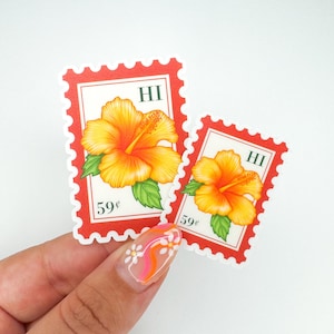 May include: Two stickers in the shape of postage stamps, featuring a vibrant orange and yellow hibiscus flower with green leaves. The stamps have a red border, the letters "HI", and the price "59¢".