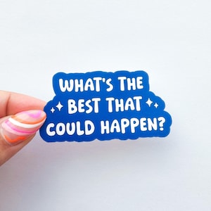 以下が含まれることがあります： 「WHAT'S THE BEST THAT COULD HAPPEN？」と書かれた白い文字が入った青いステッカー。ステッカーは雲のような形で、小さな星が2つ付いています。カラフルなマニキュアをした手でステッカーを持っています。