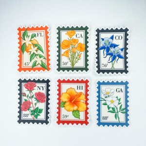 Op de afbeelding: Zes postzegels in vintage-stijl met verschillende bloemen en afkortingen van staten. De postzegels zijn oranje, groen, blauw, zwart, rood en lichtblauw. De postzegels tonen de volgende staten: FL, CA, CO, NY, HI en GA.