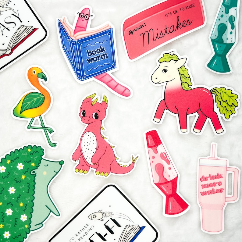 Puede incluir: Una colecci&oacute;n de pegatinas coloridas con varios dise&ntilde;os. Incluyen un drag&oacute;n rosa, un flamenco, un gusano de libro, un caballo, una l&aacute;mpara de lava y un vaso con el texto "drink more water". Tambi&eacute;n una pegatina que dice "It's ok to make mistakes".