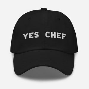May include: A black baseball cap with white embroidered text that reads "YES CHEF".