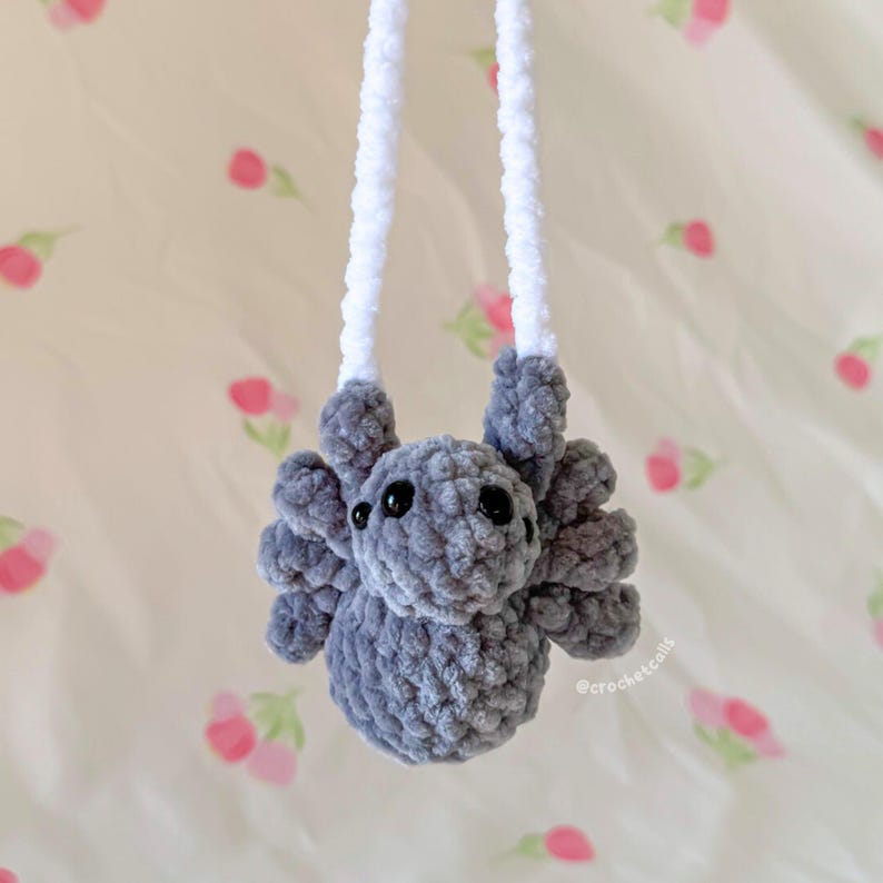 May include: A handmade gray crochet spider with eight legs and black eyes, suspended by two white cords. The plush toy is soft and fluffy, perfect for a child's room or as a unique gift. The spider is approximately 4 inches wide.