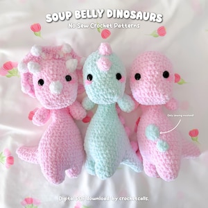 Può includere: Tre peluche di dinosauri all'uncinetto in rosa e azzurro. Il testo "SOUP BELLY DINOSAURS" e "No Sew Crochet Patterns" sono in alto. Il testo "Digital PDF download by crochetcalls" è in basso. Il testo "Only sewing involved!" è a destra.