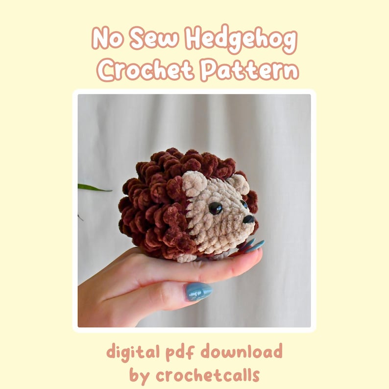 May include: A brown and beige crocheted hedgehog amigurumi toy. The hedgehog has a brown body with a beige face and black eyes. The toy is being held in a hand.