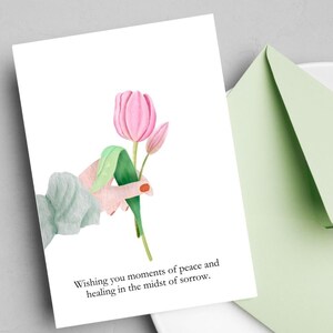 Peut inclure: Une carte de condoléances avec une illustration aquarelle d'une main tenant une tulipe rose avec des feuilles vertes. La carte dit "Wishing you moments of peace and healing in the midst of sorrow."