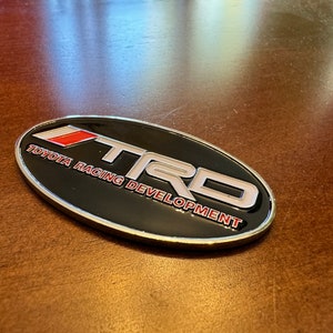Toyota TRD Logo Badge Emblem Racing Development 40mmx70mm 40 mm x 70 mm Snorkel Fender Body Rear Trunk Bumper Accessory Color Silver Black