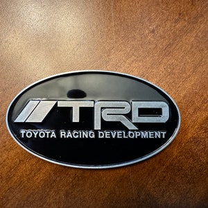 Toyota TRD Logo Badge Emblem Racing Development 40mmx70mm 40 mm x 70 mm Snorkel Fender Body Rear Trunk Bumper Accessory Color Black Silver