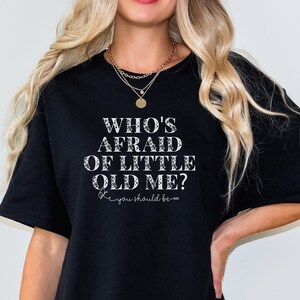 May include: Black oversized t-shirt with the text "Who's Afraid of Little Old Me? 'Cause you should be..."
