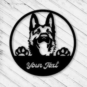 以下が含まれることがあります： 黒い金属製の壁掛けアート。円形のフレームの中にジャーマンシェパード犬のデザイン。犬の頭と足が見え、下に「Your Text」の文字。屋内または屋外での展示に適しています。