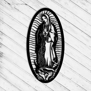 Puede incluir: Imagen en blanco y negro, cortada con láser, de la Virgen María, enmarcada en un óvalo. La obra presenta detalles intrincados de su túnica y halo, con un fondo texturizado. Montada sobre una superficie de tablones de madera clara.