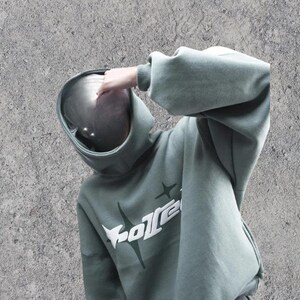 Puede incluir: Una sudadera con capucha verde con un gr&aacute;fico blanco de una estrella y la palabra "GoZen" en la parte delantera.