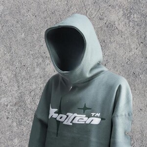 Puede incluir: Una sudadera con capucha verde salvia con un gr&aacute;fico blanco de una estrella y la palabra "Rotten" con un s&iacute;mbolo TM.