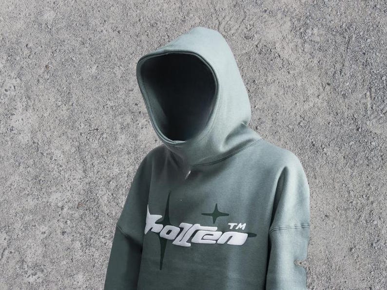 Puede incluir: Una sudadera con capucha verde salvia con un gr&aacute;fico blanco de una estrella y la palabra "Rotten" con un s&iacute;mbolo TM.
