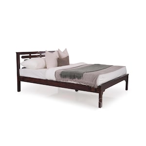 Può includere: Un letto con struttura in legno marrone scuro con testata a doghe e un design semplice. Il letto è rivestito con biancheria da letto bianca e una coperta grigia.
