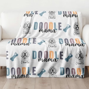May include: White throw blanket with a repeating pattern of a doodle dog illustration, bone shapes, and the words "DOODLE mama" in various colors. The dog's name, "Charlie," is also printed on the blanket.