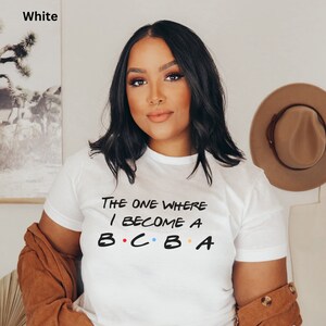 Könnte beinhalten: Weißes T-Shirt mit dem Aufdruck "The One Where I Become A B.C.B.A.".