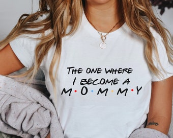 May include: White t-shirt with the text "The One Where I Become A M.O.M.M.Y." in black with colorful dots.