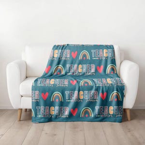 May include: A teal blue fleece blanket with a repeating pattern of rainbows, hearts, and the text "TEACHER Mrs. Johnson".