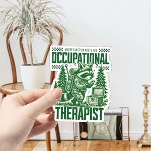May include: Green and white sticker with a raccoon wearing a backpack and holding a phone. The text reads "Where function meets fun Occupational Therapist".