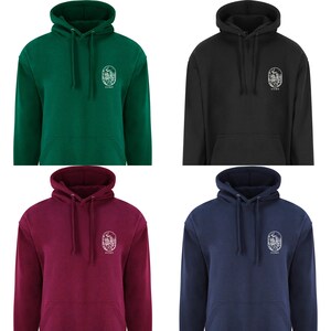 K&ouml;nnte beinhalten: Vier Kapuzenpullover in verschiedenen Farben: gr&uuml;n, schwarz, burgunderrot und marineblau. Jeder Pullover zeigt eine wei&szlig;e Grafik einer Waldszene mit dem darunter gedruckten Wort "HOME".