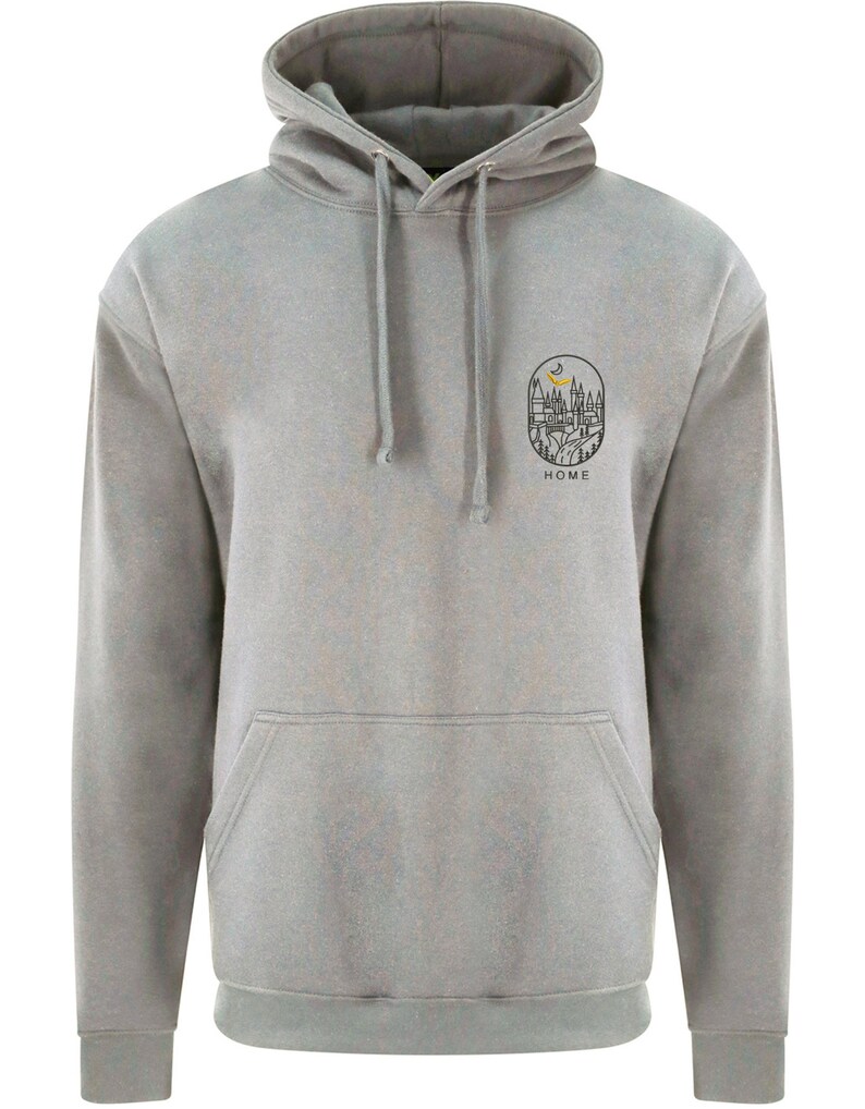 K&ouml;nnte beinhalten: Ein grauer Kapuzenpullover mit einem kleinen Schwarzwei&szlig;-Motiv eines Hauses mit einer Mondsichel und B&auml;umen. Das Motiv befindet sich in einem Kreis mit dem Wort "HOME" darunter.