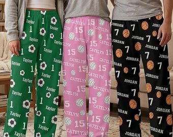 May include: Three pairs of lounge pants featuring personalized names and numbers. The green pair displays the name Taylor and number 1 with soccer balls. The pink pair shows Catelyn and 15 with volleyballs. The black pair features Jordan and 7 with basketballs.