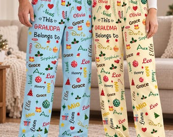 May include: Two pairs of pajama pants, one light blue and one cream, both featuring a repeating Christmas-themed pattern of names, hearts, bells, ornaments, and trees. The blue pants read This GRANDPA Belongs to, while the cream pants read This GRANDMA Belongs to.