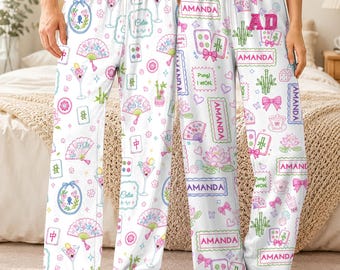 May include: White pajama pants featuring a colorful repeating pattern of mahjong tiles, folding fans, bamboo stalks, lotus flowers, cocktails, and pink bows. The design includes the text AMANDA, Celia, and Pung! I WON in various frames.