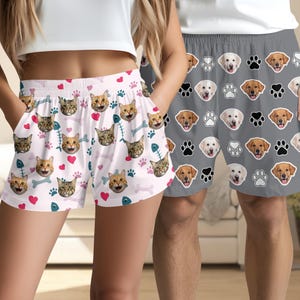 May include: A pair of white and pink shorts with a cat face pattern. The shorts have a drawstring waist and are made of a soft, comfortable fabric. A pair of grey shorts with a dog face pattern. The shorts have a drawstring waist and are made of a soft, comfortable fabric.