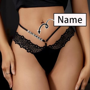 Può includere: Lingerie nera in pizzo con un sottile cinturino che recita "Princess" in strass.