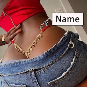 May include: A red string thong with a gold chain attached to it. The chain has charms with the letters "GODIVA" hanging from it.