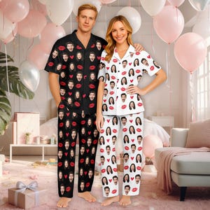 May include: Matching pajama sets, one black and one white, each featuring a repeating pattern of faces, red lips, and hearts. The black set has a short-sleeved button-down shirt and pants. The white set has a short-sleeved button-down shirt and pants.