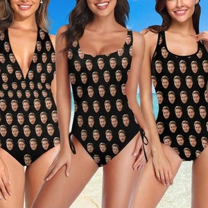 May include: Three black one-piece swimsuits featuring a repeating pattern of a person's face. The swimsuits have different necklines, including a deep V-neck and scoop neck styles, with some designs featuring side ties at the hip area.