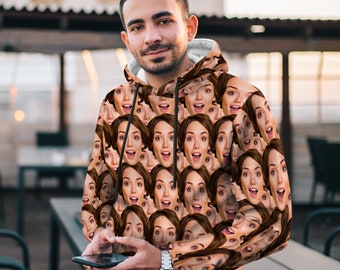 May include: A black hooded sweatshirt with a repeating pattern of a person's face. The face is smiling and has a surprised expression.