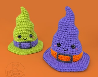 May include: Two crocheted witch hats with smiling faces. One hat is green with a purple band and the other is purple with an orange band.