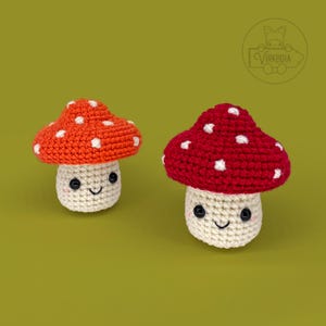 May include: Two crocheted mushroom plushies with white dots on their red and orange caps. The mushrooms have white bodies with black eyes and a smiling mouth.