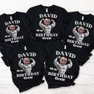 May include: Black t-shirts featuring a graphic of a man's face on a muscular body. The text "DAVID", "40th BIRTHDAY Crew" is printed in white. These shirts are likely for a birthday celebration.