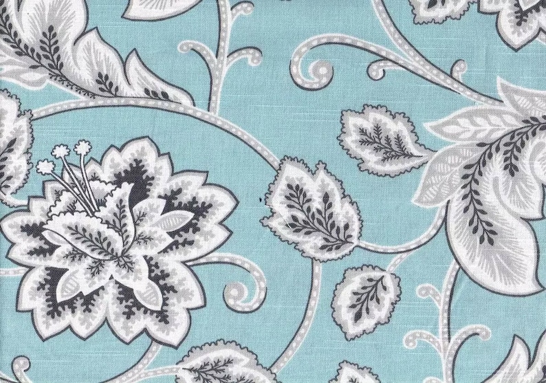 May include: A blue fabric with a white and gray floral pattern. The pattern features large flowers and leaves.