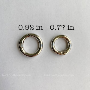 May include: Two silver metal key rings with a spring clasp. The larger ring measures 0.92 inches in diameter and the smaller ring measures 0.77 inches in diameter.