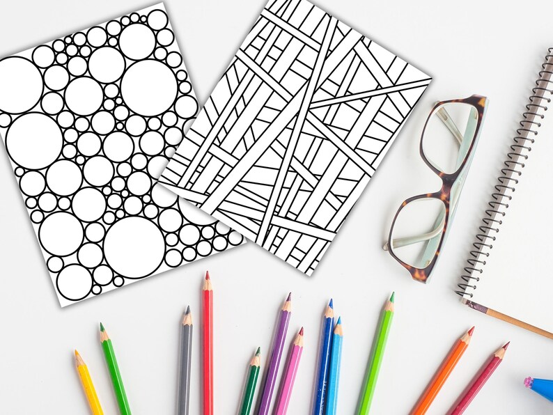 May include: Two black and white coloring pages, one with a pattern of overlapping circles and the other with a geometric pattern of intersecting lines.  A set of colored pencils and a pair of glasses are also in the image.