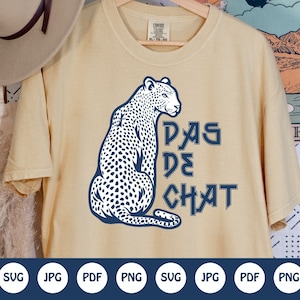 May include: A beige t-shirt with a blue graphic of a leopard with the text "PAS DE CHAT" printed on it.