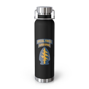 May include: Black stainless steel water bottle with a silver lid and carrying handle. The bottle has a graphic of a yellow and blue special forces airborne insignia with the text "SPECIAL FORCES AIRBORNE".