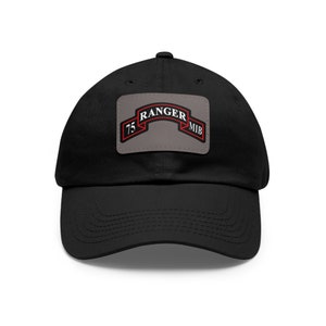 Op de afbeelding: Zwarte baseball cap met een gebogen klep. De cap heeft een rechthoekige patch met de tekst "RANGER" boven een banner, "75" links en "MIB" rechts. De patch heeft een grijze achtergrond met rode en zwarte accenten.
