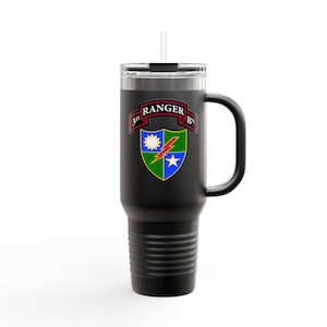 Può includere: Tazza da viaggio nera con manico e cannuccia. La tazza presenta un emblema colorato con la scritta "RANGER" e "3D BN". L'emblema include un sole, un fulmine e una stella.