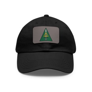 May include: A black baseball cap with a green, yellow, and white patch featuring a triangle with a sword inside. The patch is sewn onto the front of the cap.
